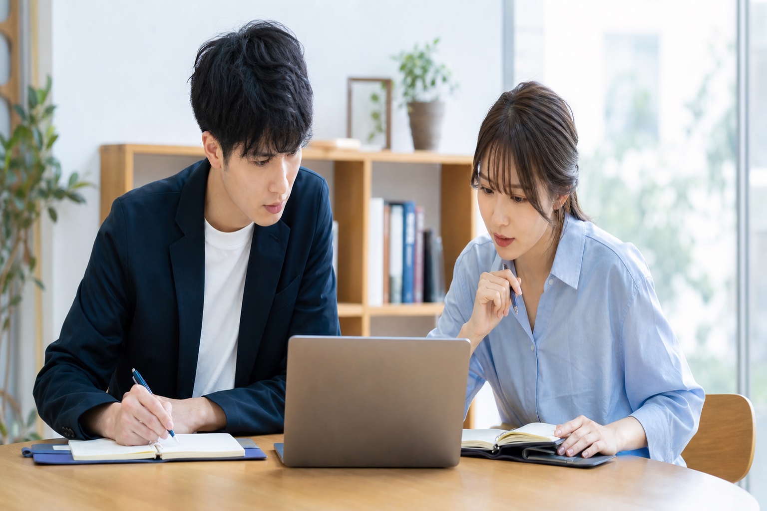 就活生の男女がノートパソコンと手帳を広げて企業研究をしている様子
