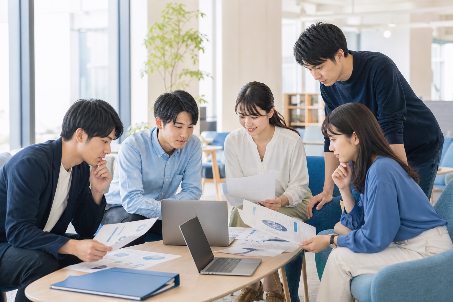 就活生数人がオフィスラウンジでノートパソコンと資料を囲んで日立グループの企業研究をしている様子のイラスト